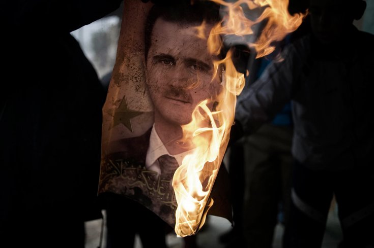 عنصر من الجيش السوري الحر يحرق صورة لبشار الأسد في بلدة القصير 25 كانون الثاني /يناير 2012