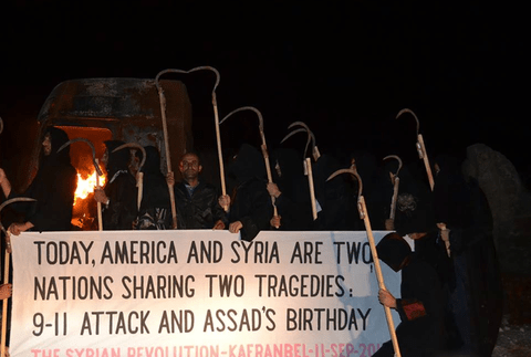 نشطاء في كفرنبل يرتدون زي الحداد أثناء احتجاج يوم 11 أيلول/سبتمبر، عيد ميلاد الرئيس السوري بشار الأسد.