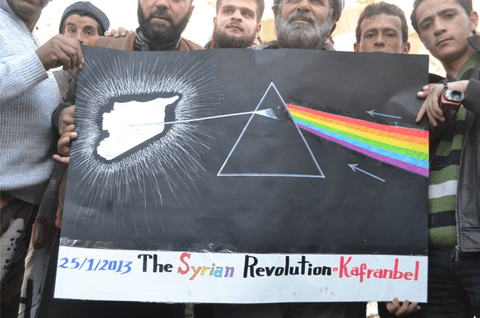 متظاهرون في كفرنبل، مع ملصق يشير إلى ألبوم بينك فلويد بينك فلويد "الجانب المظلم من القمر".